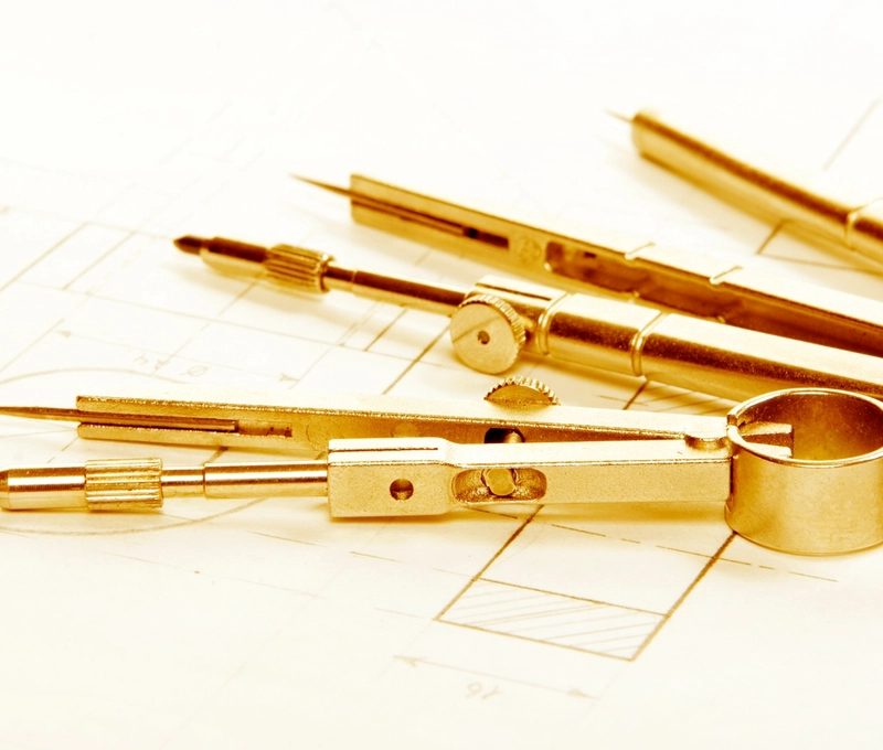 A fountain pen, glasses and drawing tools on sheets of paper
