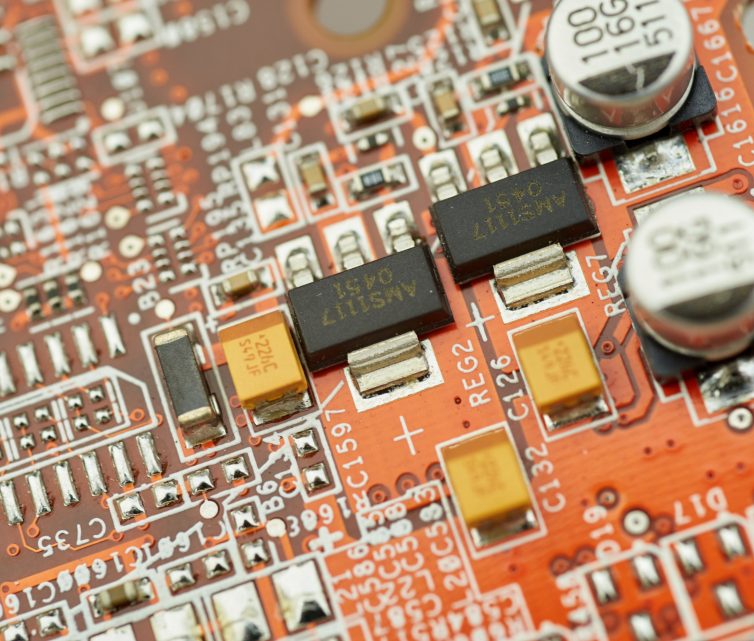 A close-up of a circuit board with electronic parts and capacitors