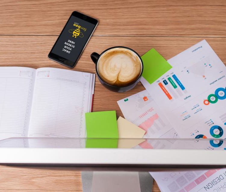 A desk with an open notebook, coffee and papers, seen from above
