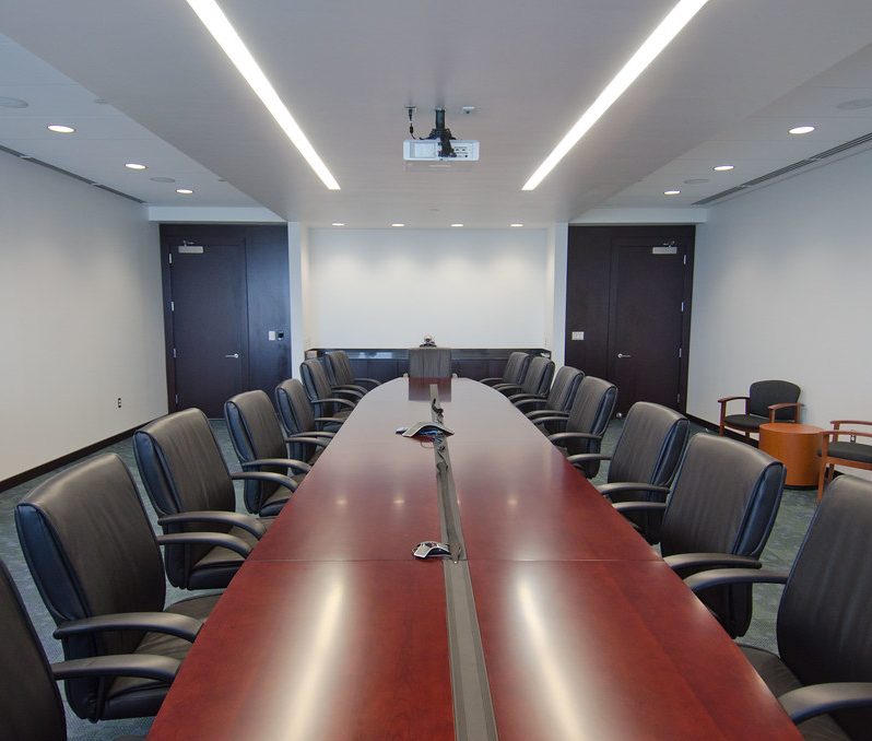 A meeting room with a long table and rows of chairs